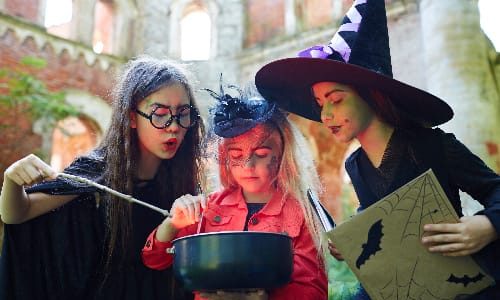 Gloomy halloween witches saying black magic spells over pot with poisonous brew